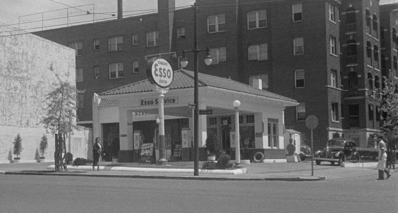 Photo of a freshly-painted Esso service station at an urban street corner. 
