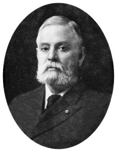 Photographic portrait of a man with bushy white mutton chops.