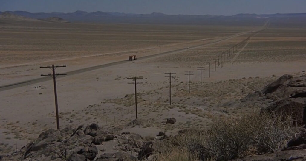 Film still panoramic shot of Kowalski driving into the distance along a desolated stretch of route 50.