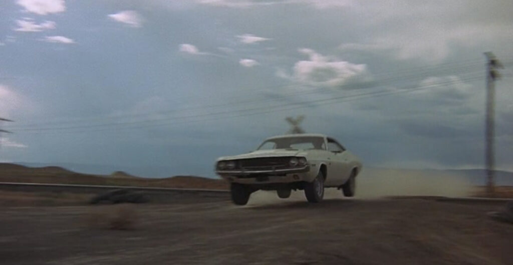 Film still of Kowalski's Dodge Challenger catching air as it launches over railroad tracks.